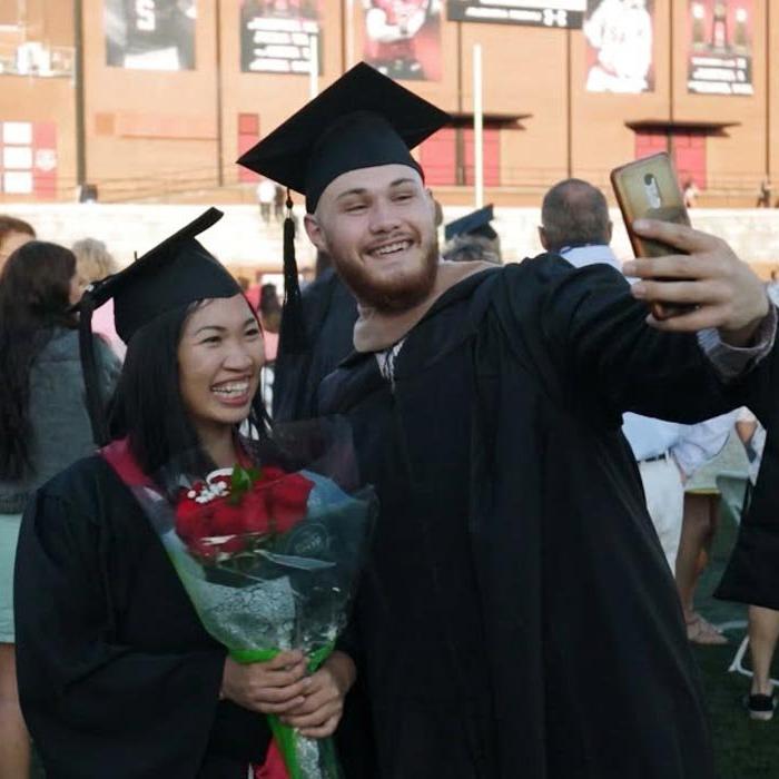 Two students take a selfie at end of commencement ceremony